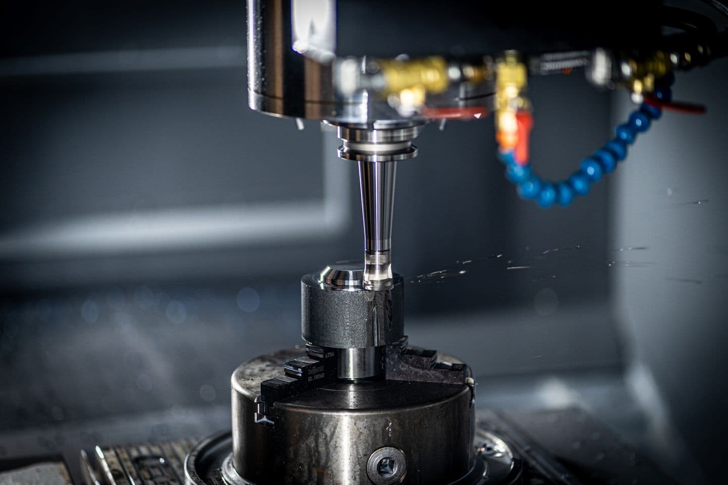 CNC spindle machining a metal component inside an enclosed machine.