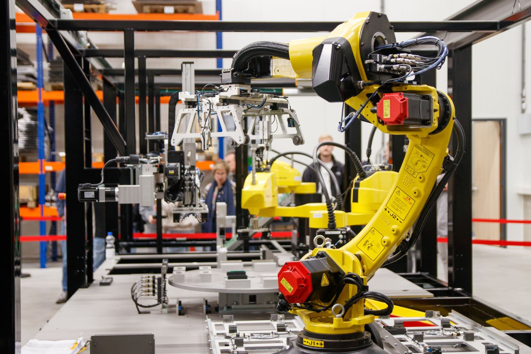 Yellow industrial robot with tooling and surrounding production equipment.