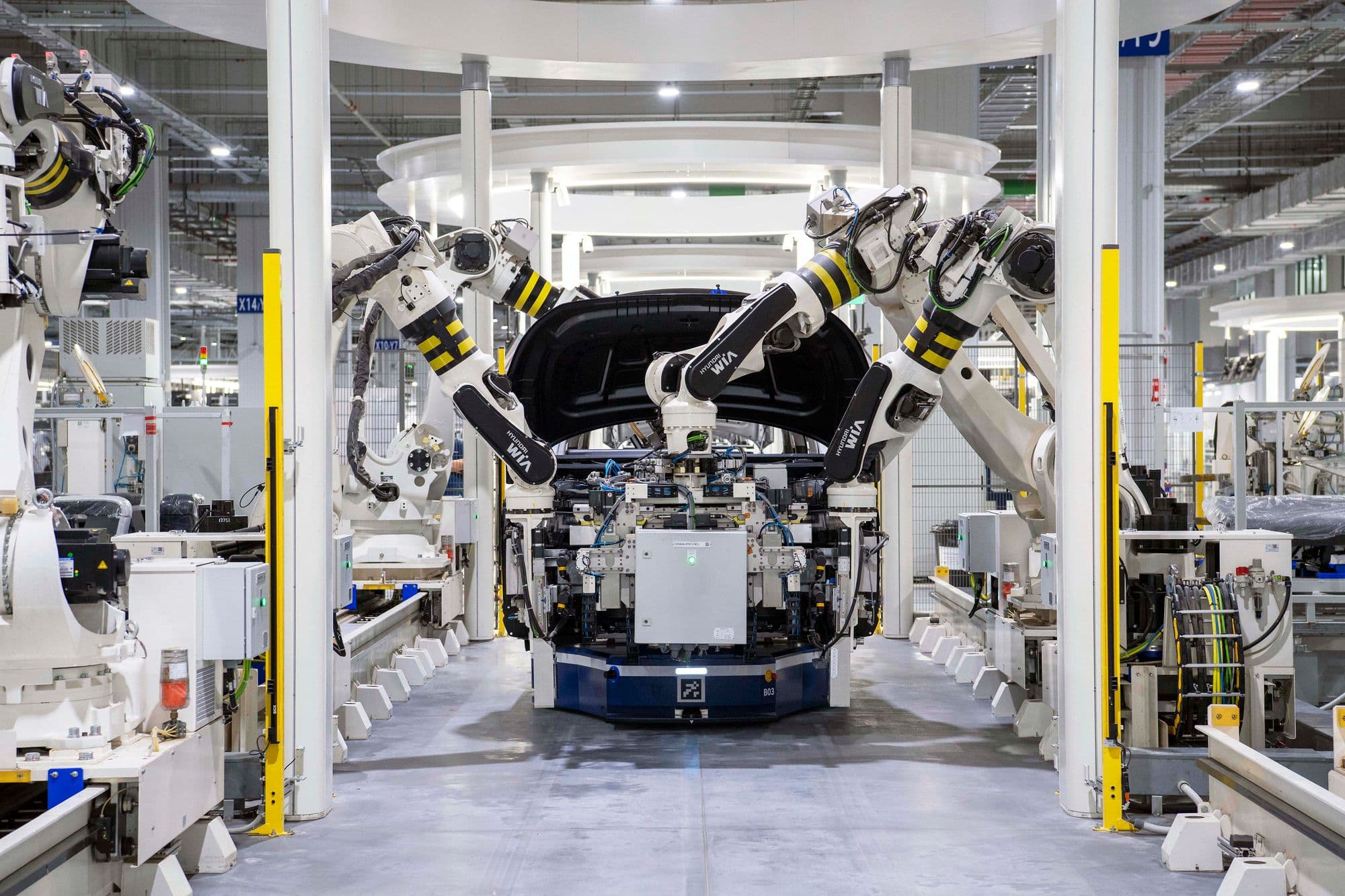 Robotic arms arranged around a vehicle body on an automotive assembly line.